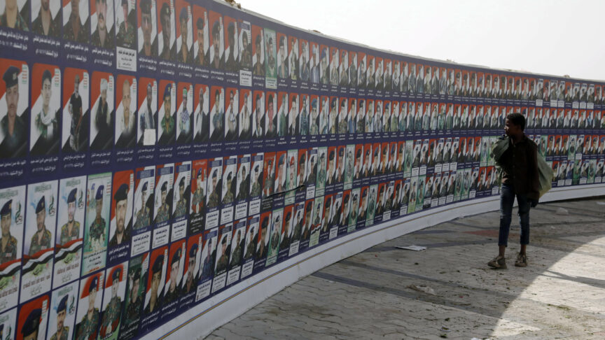 Jemenský chlapec míjí transparent s portréty zesnulých bojovníků Houthi údajně zabitých v dlouhém válečném konfliktu