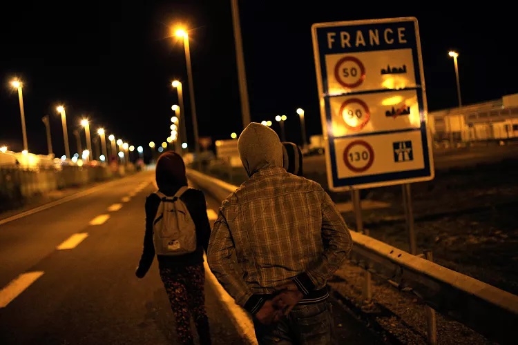 Migranti jdou po silnici mimo oblast Eurotunelu v Calais v severní Francii