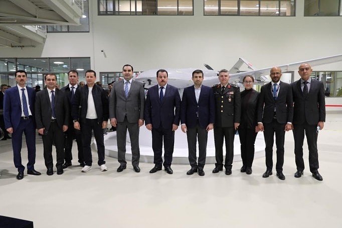 Tádžická ministryně obrany Sherali Mirzo, postava uprostřed s knírkem, pózující na fotografii s představiteli turecké armády, zástupci společnosti Baykar, istanbulského výrobce obrany, a dalšími před dronem Bayraktar.