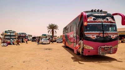 Osobní autobusy 25. dubna 2023 čekají na evakuované na odpočívadle Multaga poblíž Ganetti v Súdánu. Východní Afričan se dozvěděl, že každý den asi 20 vozidel přepraví nově příchozí ze Súdánu do města Metma Yohannes na etiopském hraničním přechodu do města Gondar